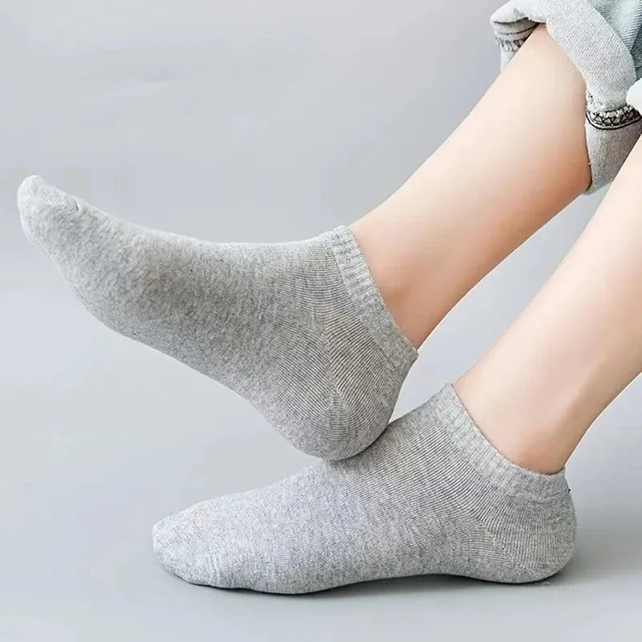  Person wearing light grey no-show socks while sitting on a couch, showcasing breathability.
