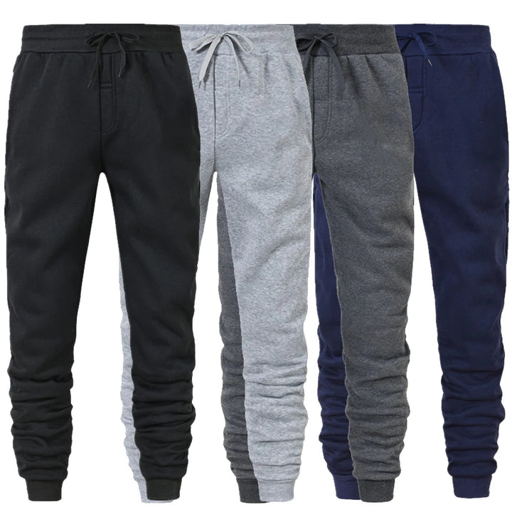  Three pairs of men's athletic sweatpants in black, gray, and navy blue, featuring a tapered fit and elastic waistband.
