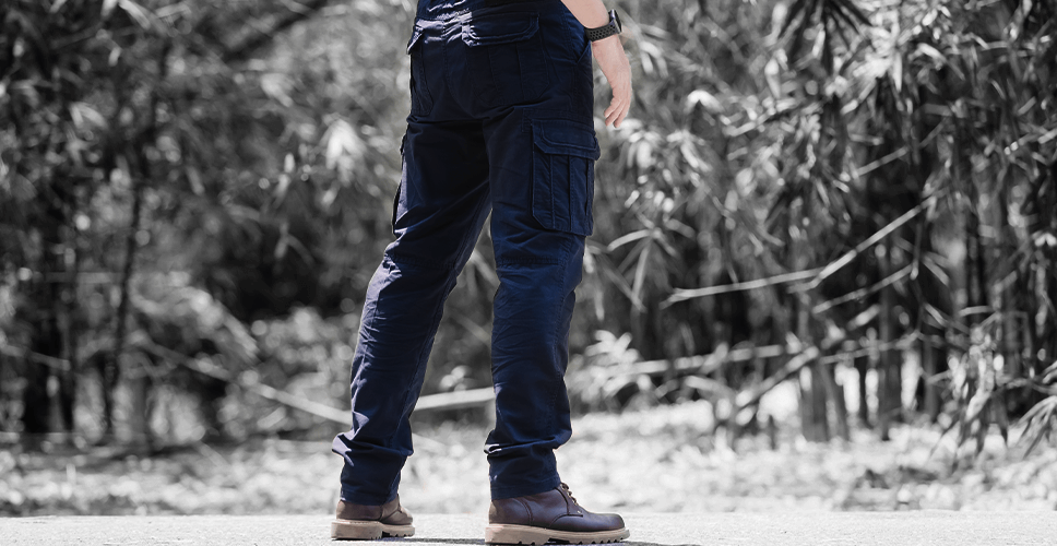 Person wearing dark blue pants and shoes standing outdoors with a natural background