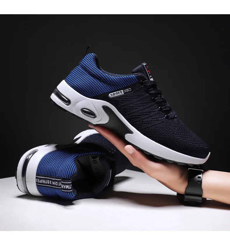 A stylish pair of navy blue and black running sneakers with a breathable mesh upper and cushioned sole, displayed in hand against a dark background.