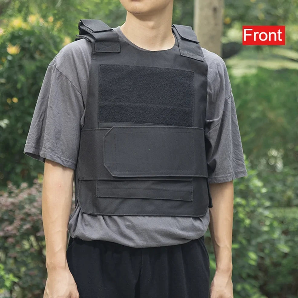 Person wearing a black tactical vest with a green outdoor background