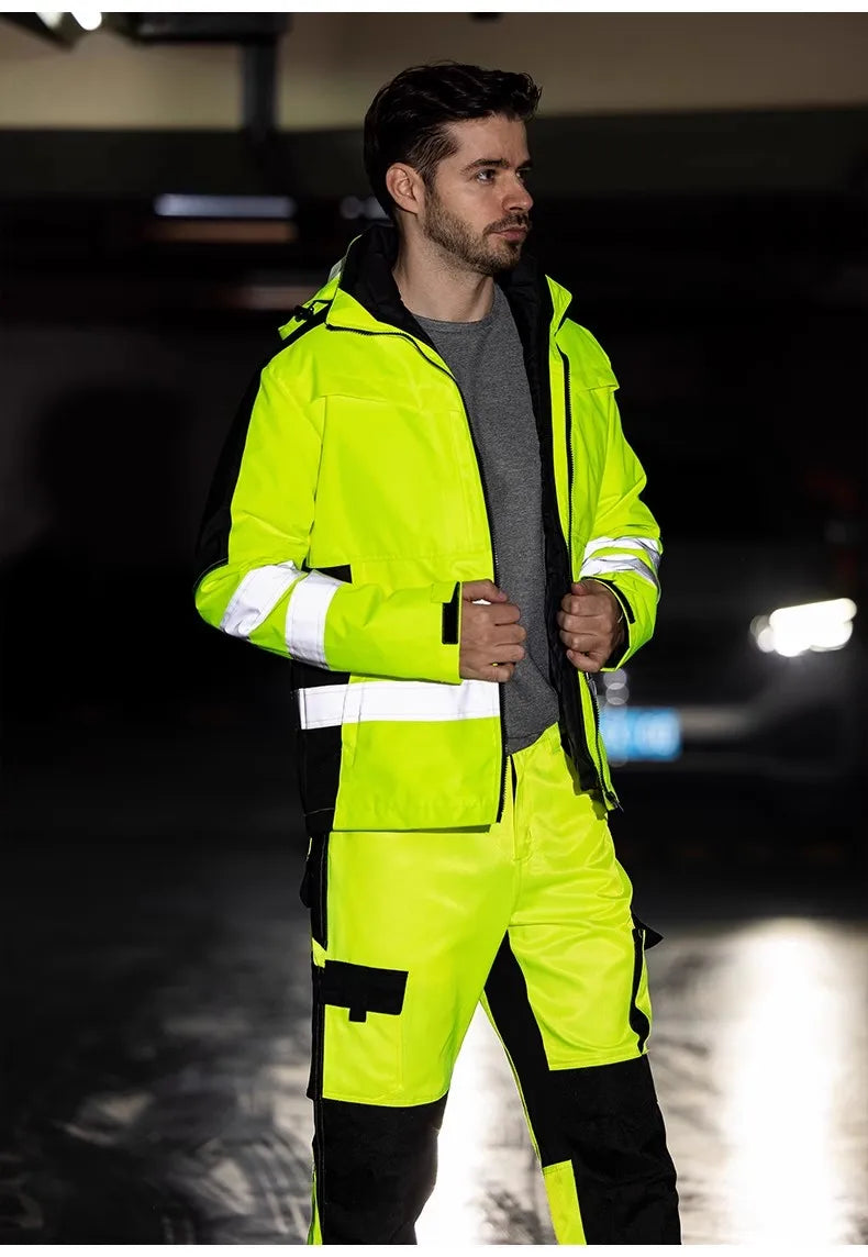 Person wearing a bright yellow safety jacket and pants in a dark setting