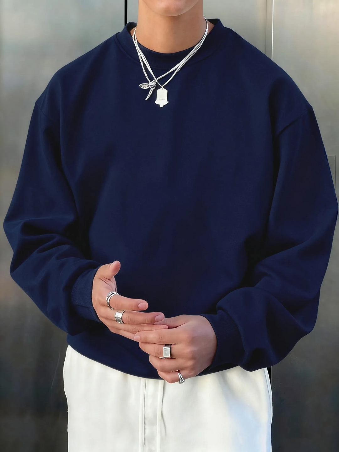 Person wearing a navy blue sweatshirt and white pants against a neutral background