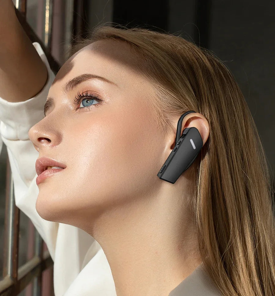Woman wearing a black wireless earbud with a blurred indoor background
