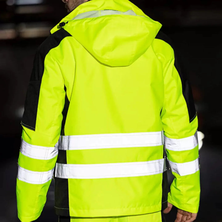 Person wearing a bright yellow reflective jacket with black accents on a dark background