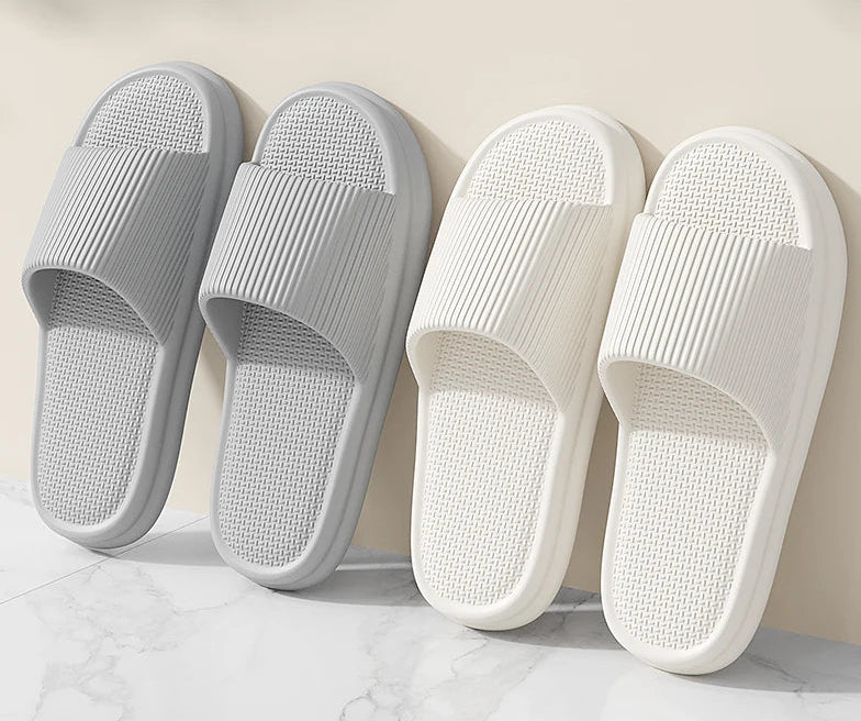 Two pairs of slippers, one gray and one white, on a light background with text above.