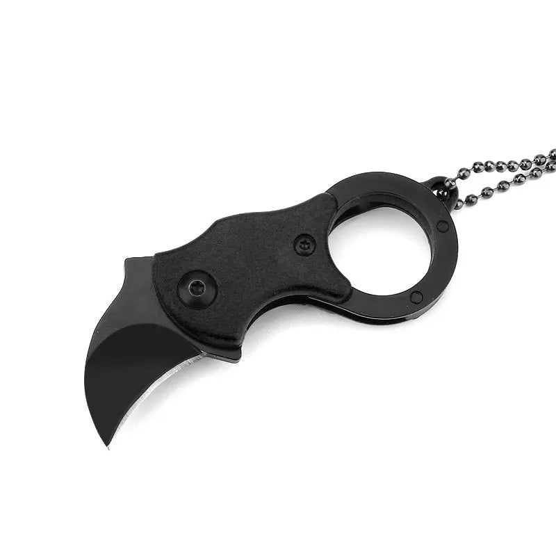 Knife with keyring laid on wooden surface beside multitool