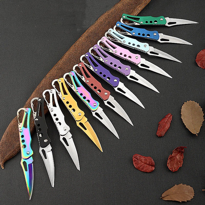Set of colorful pocket knives on a dark surface with leaves.