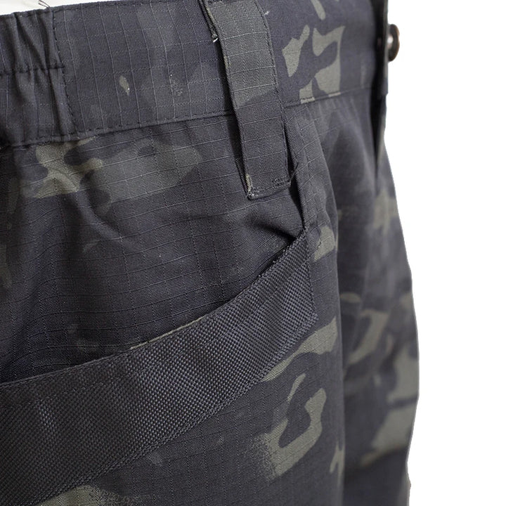Close-up of camouflage pants with a pocket and strap detail on a white background