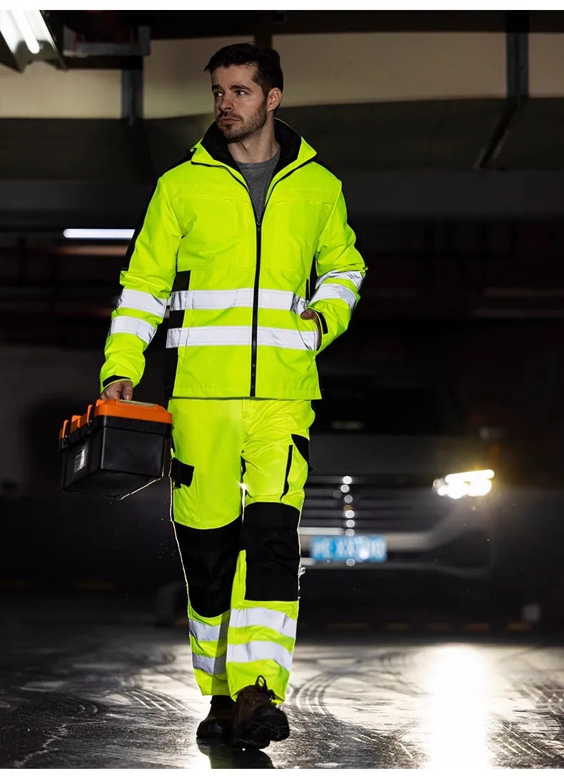 Person wearing a high-visibility safety suit holding a toolbox in a dark parking garage.