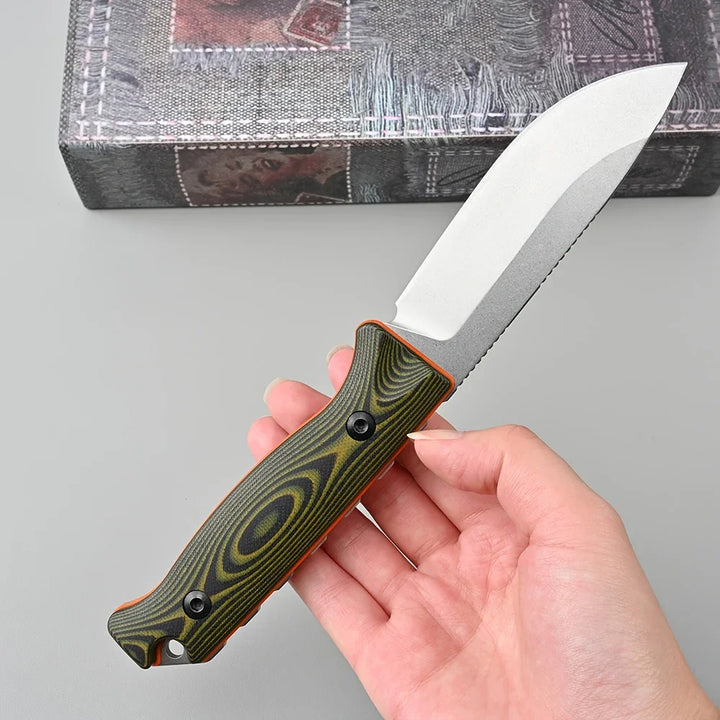 Hand holding a folding knife with a green and orange handle against a gray background