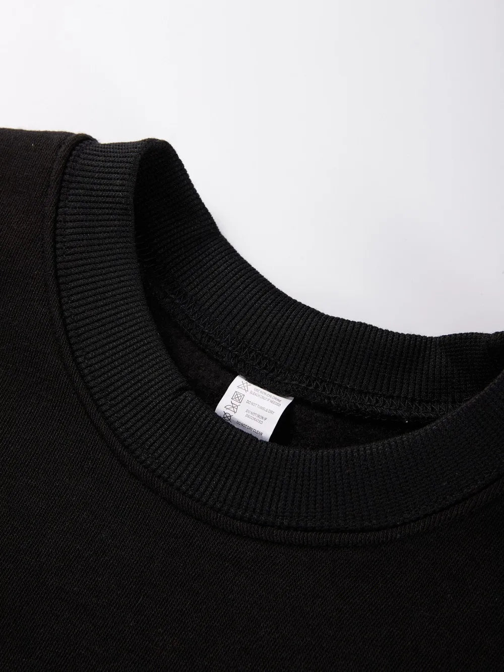 Close-up of a black sweater collar with a visible label on a white background