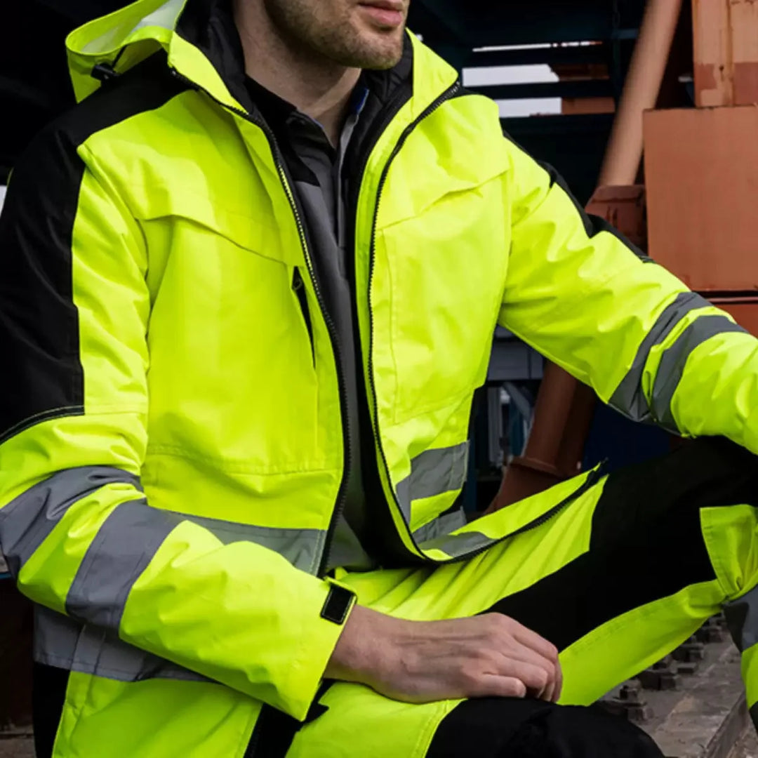 Person wearing a bright yellow safety jacket with reflective stripes.