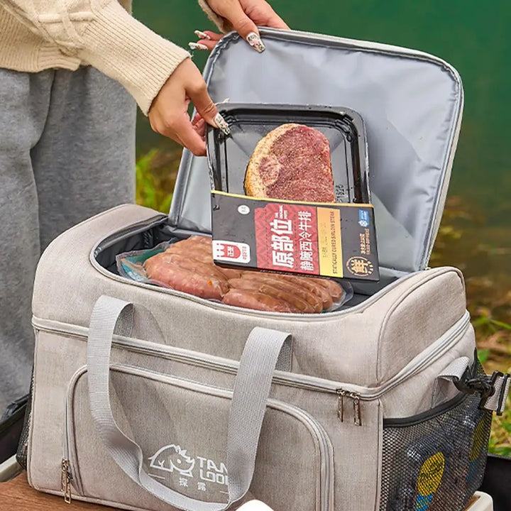 Person opening a gray cooler bag containing food items with a visible brand logo.