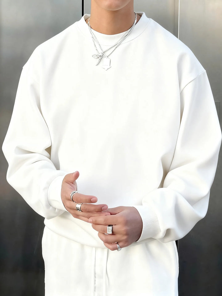 Person wearing a white hoodie and pants with a neutral background