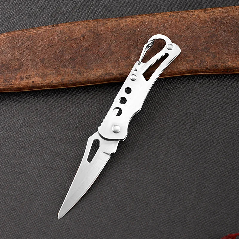 Silver pocket knife on a dark textured surface with a wooden object in the background