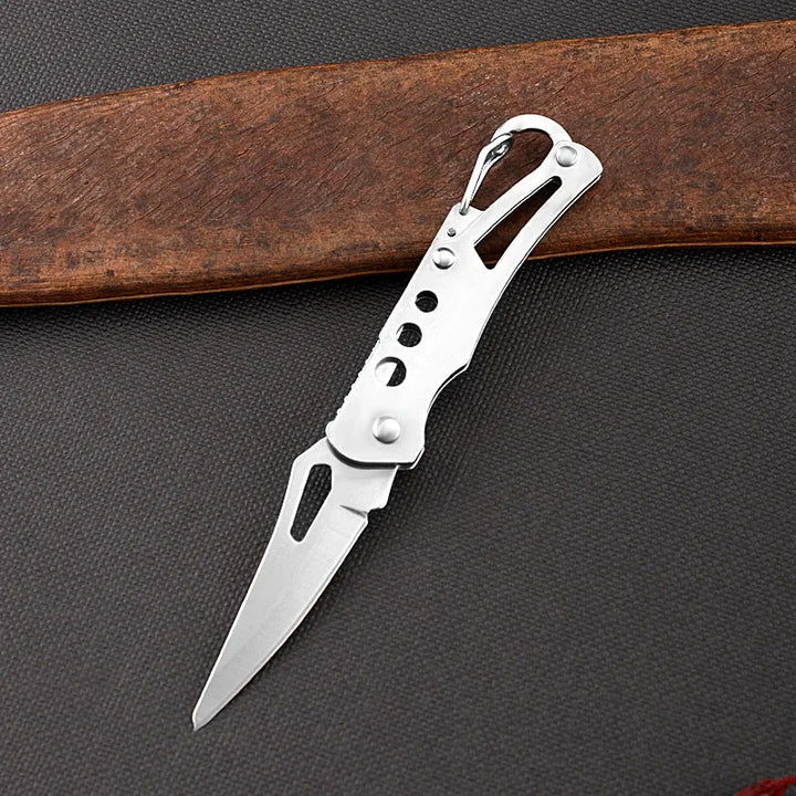 Silver pocket knife on a dark textured surface with a wooden object in the background