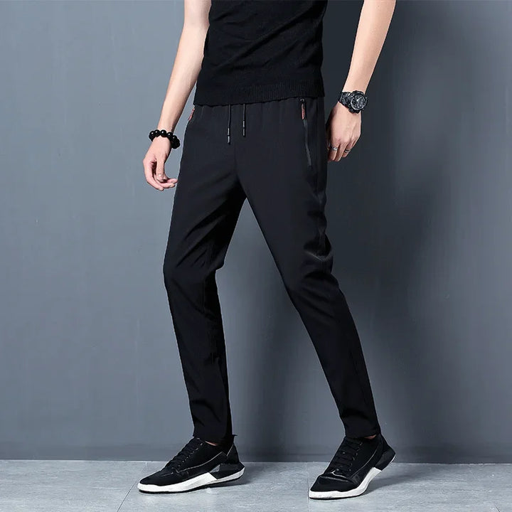 Person wearing black pants and black shoes on a gray background