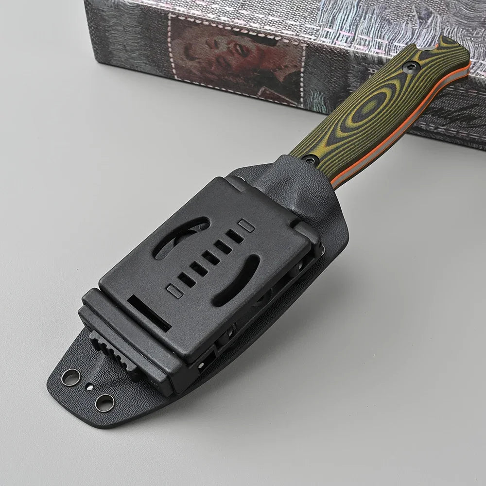 Black sheath with a knife featuring a green and orange handle on a gray surface.
