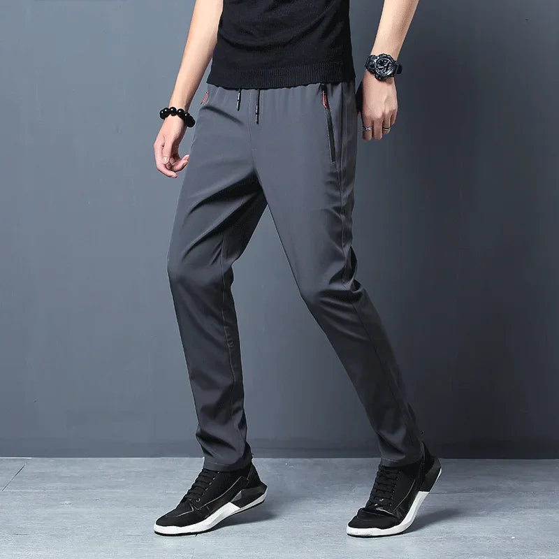 Person wearing gray pants and black sneakers on a gray background