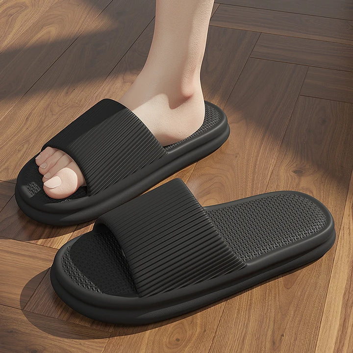 Black slippers worn on a wooden floor