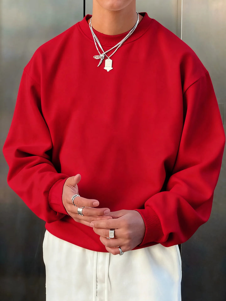 Person wearing a red sweatshirt and white pants with a neutral background