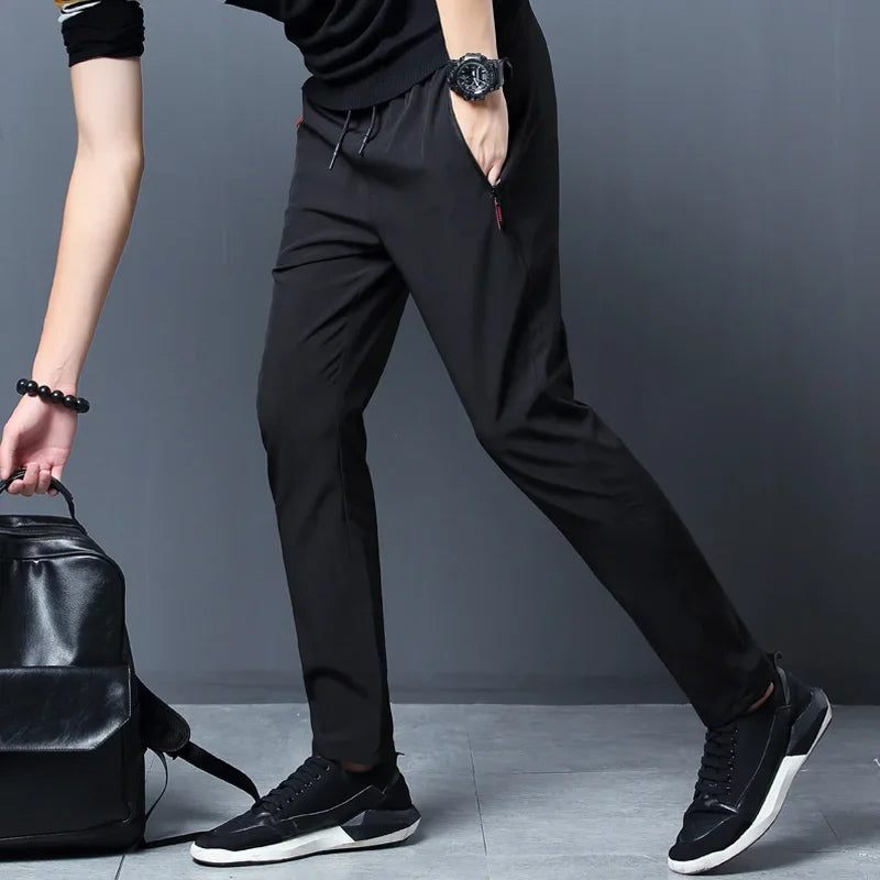 Person wearing black pants and shoes with a black backpack on a gray background
