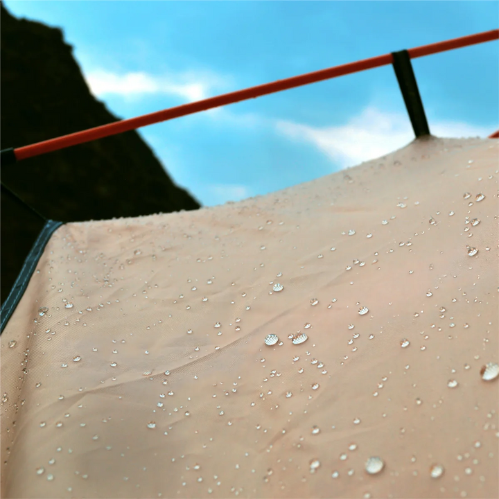 Close-up of a tent with water droplets on its surface against a blue sky.