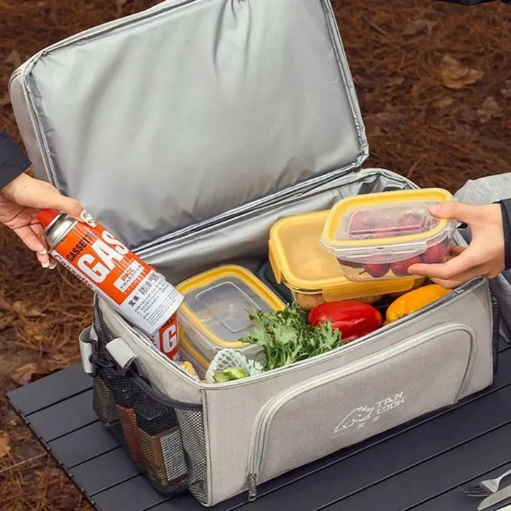 Insulated lunch bag with compartments filled with food and a person using a can of spray on it.