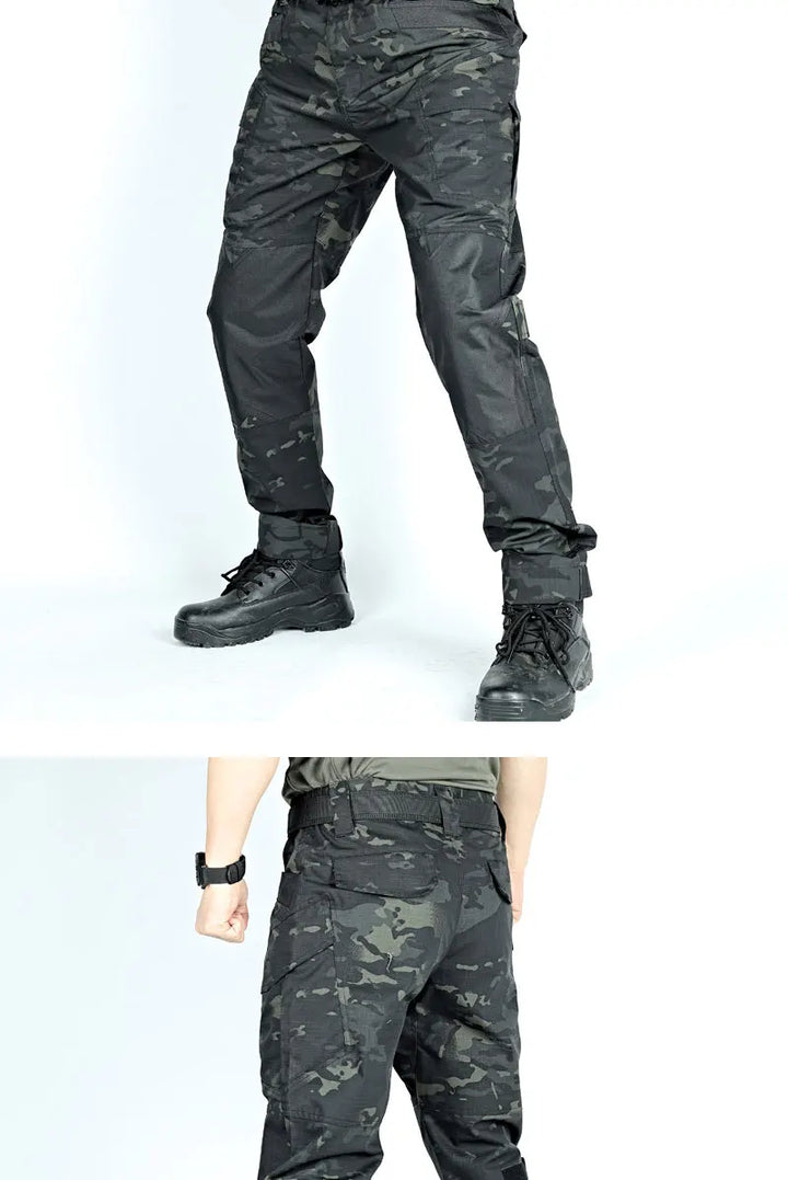Black camouflage pants worn by a person on a white background