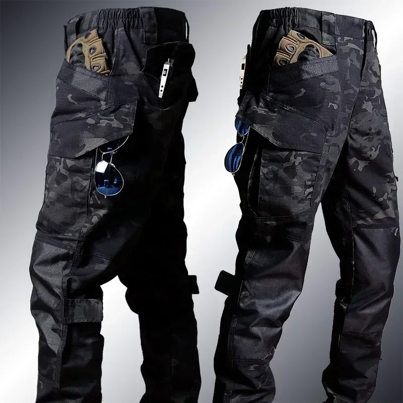 Black camouflage tactical pants shown from front and back on a gradient background