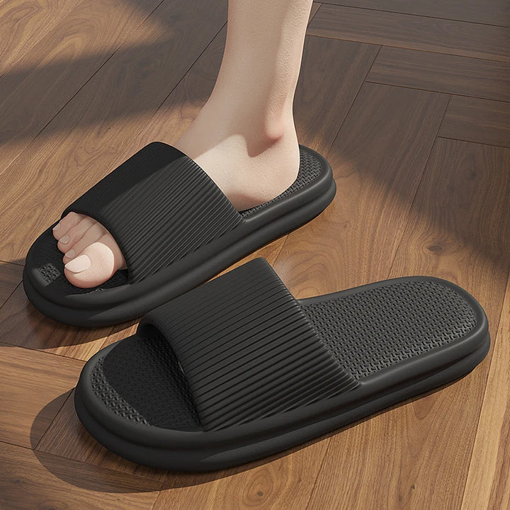 Black slippers worn on a wooden floor