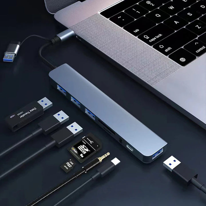 USB hub connected to a laptop with various USB devices on a dark surface