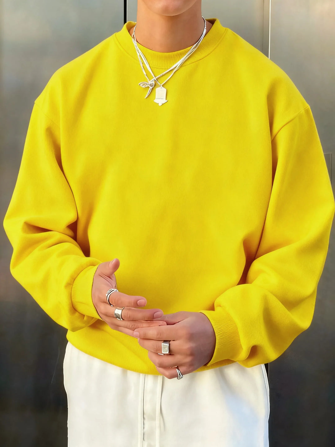 Person wearing a bright yellow sweatshirt and white pants against a neutral background