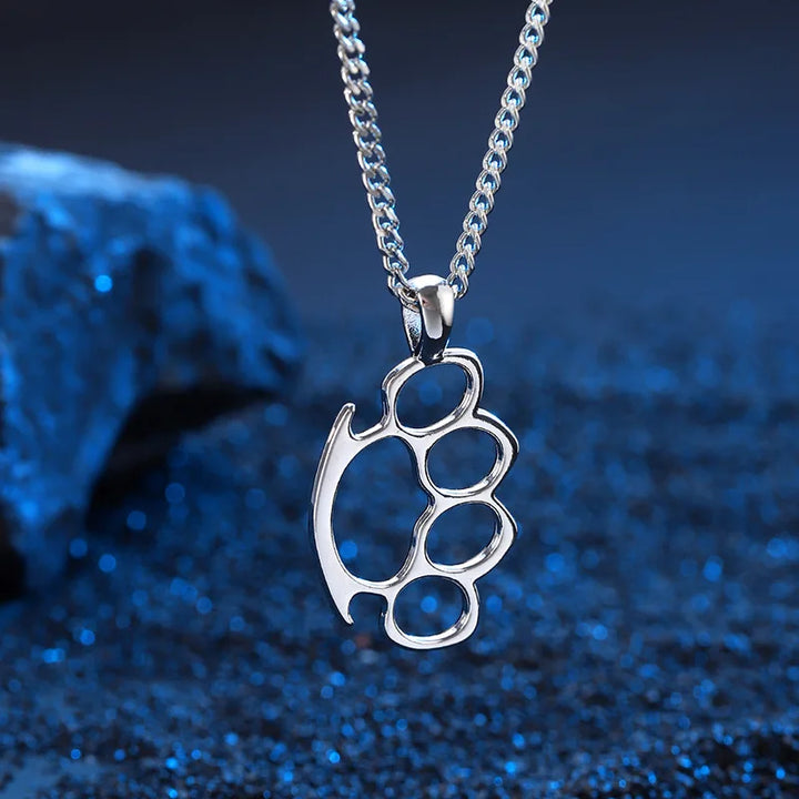 Silver knuckle duster pendant on a chain against a blue textured background