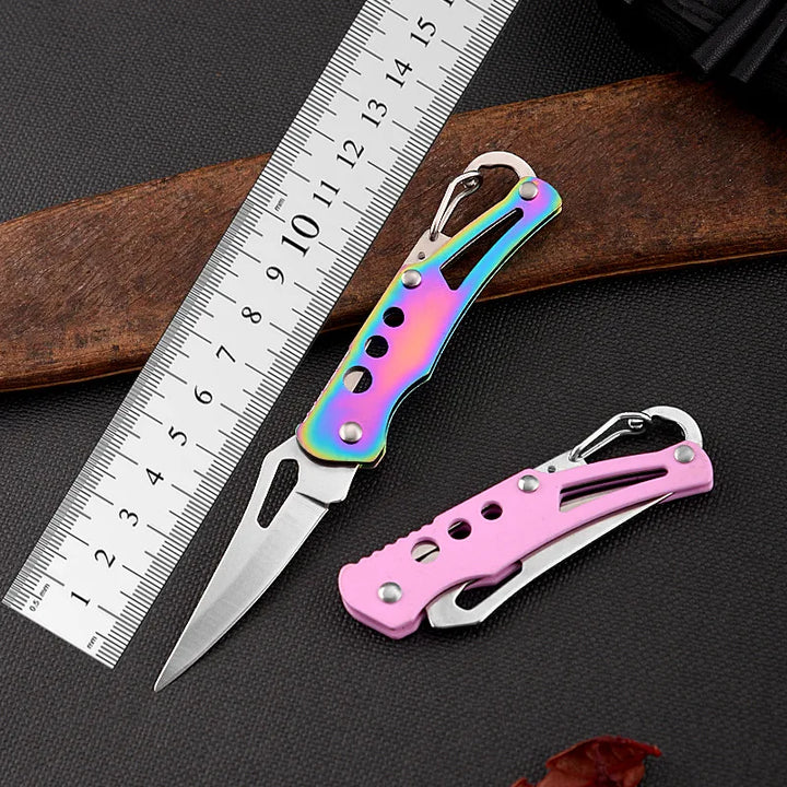 Two colorful pocket knives on a dark surface with a ruler for scale.