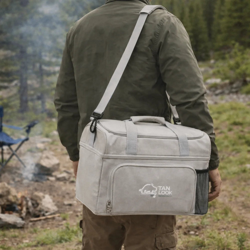 Person carrying a gray duffel bag with 'TAN LOOK' branding in a forest setting.