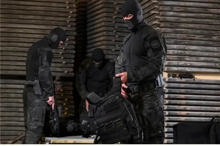 Three individuals in full tactical gear standing in a warehouse setting.