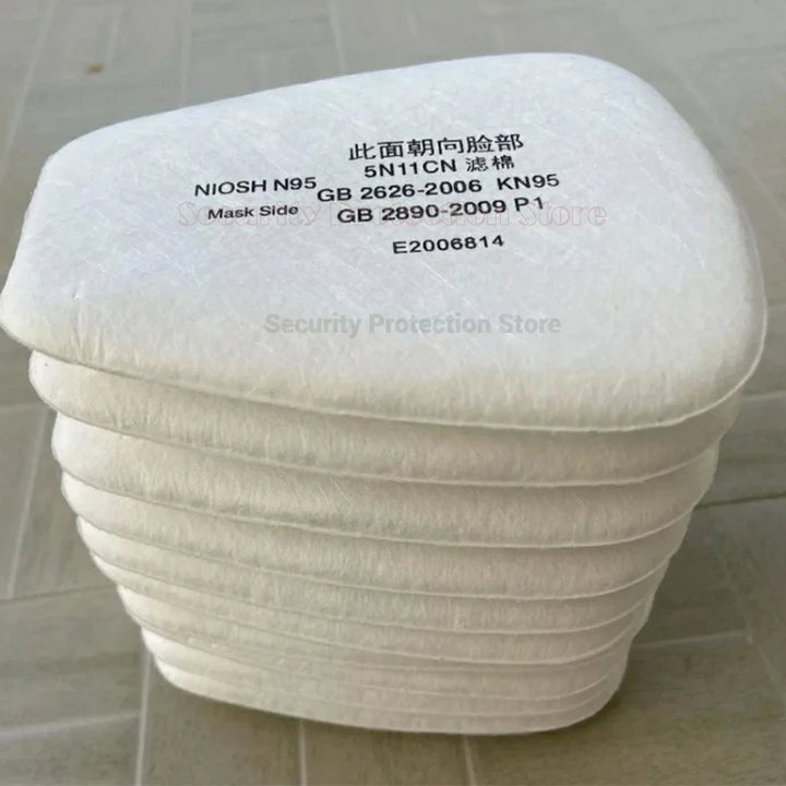 Stack of N95 face mask filters with certification labels on a tiled floor.