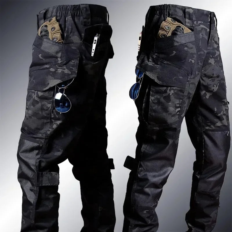 Black camouflage tactical pants shown from front and back on a gradient background