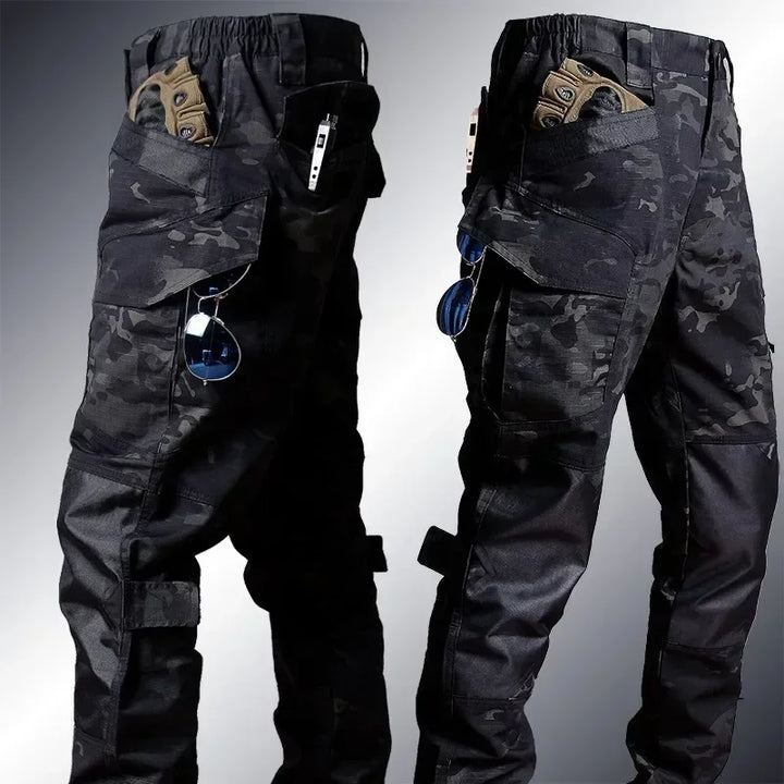 Black camouflage tactical pants shown from front and back on a gradient background
