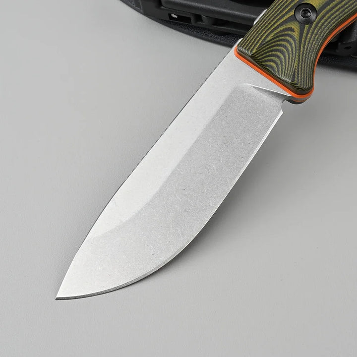 Knife with a green and orange handle on a gray background