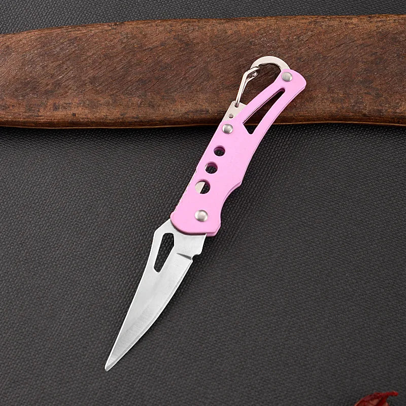 Pink folding knife on a dark surface with a wooden object in the background