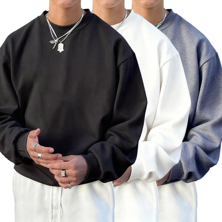 Three people wearing black, white, and gray sweatshirts with white pants.