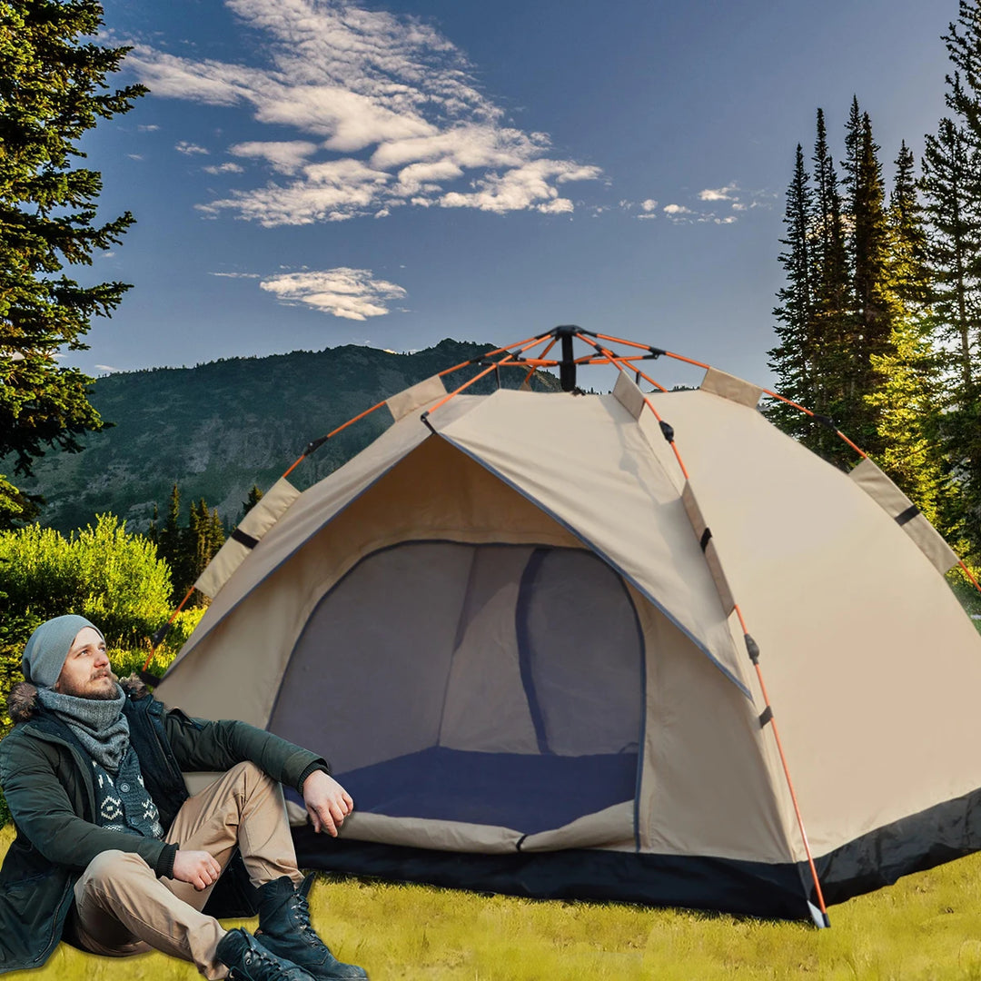 Man sitting in front of a tent in a mountainous area with trees and blue sky.