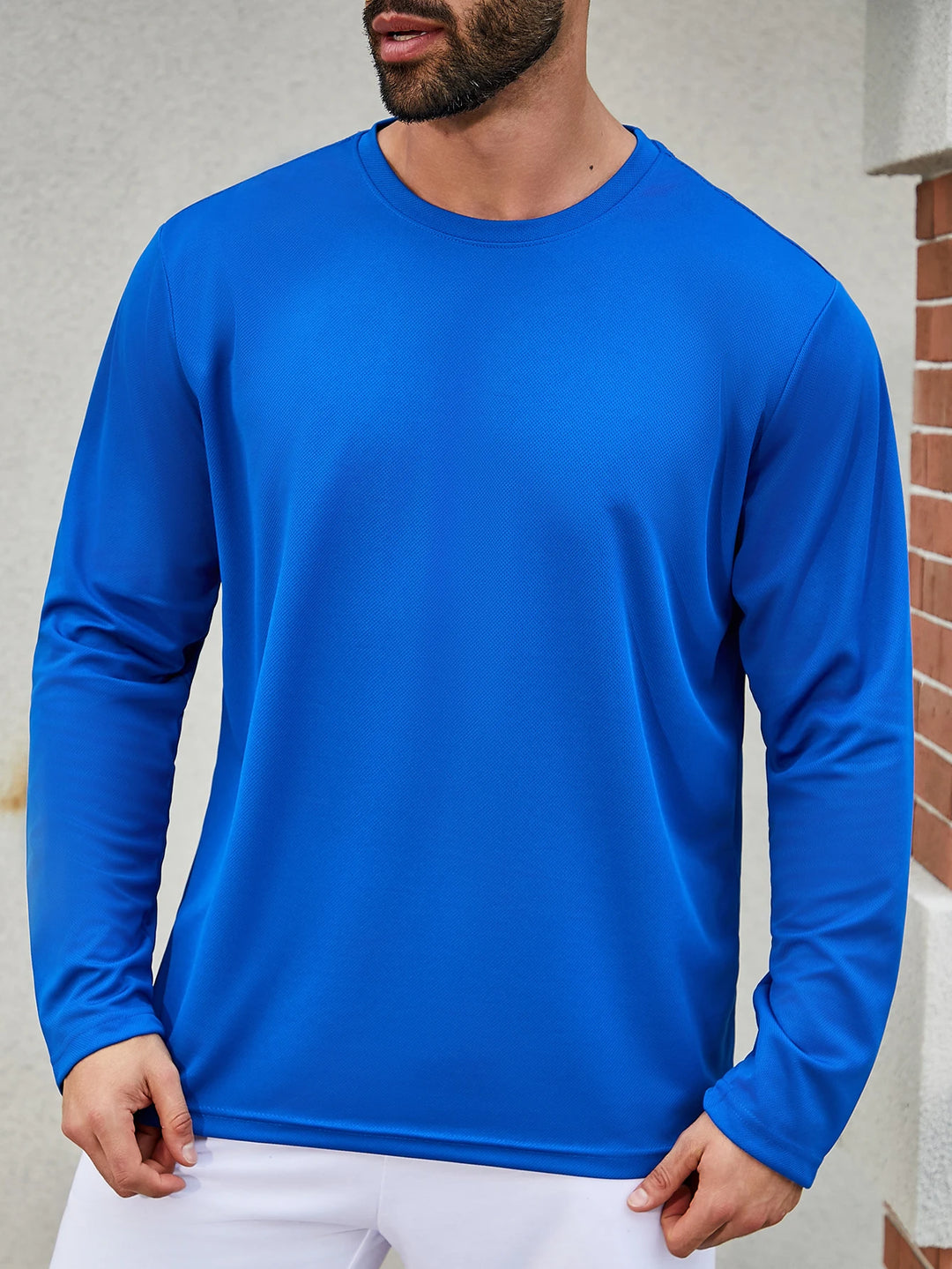 Man wearing a blue long-sleeve shirt against a neutral background