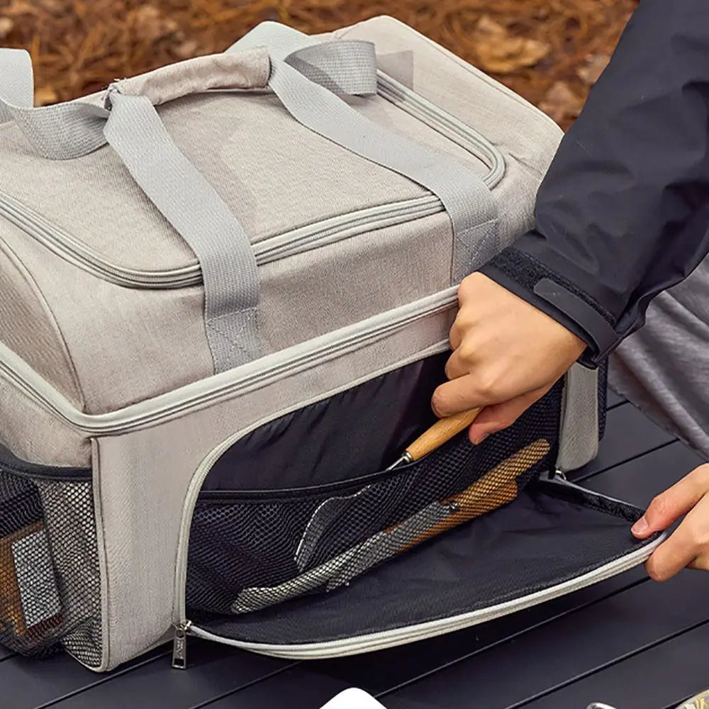 Person opening a gray pet carrier with a dog inside on a wooden surface.
