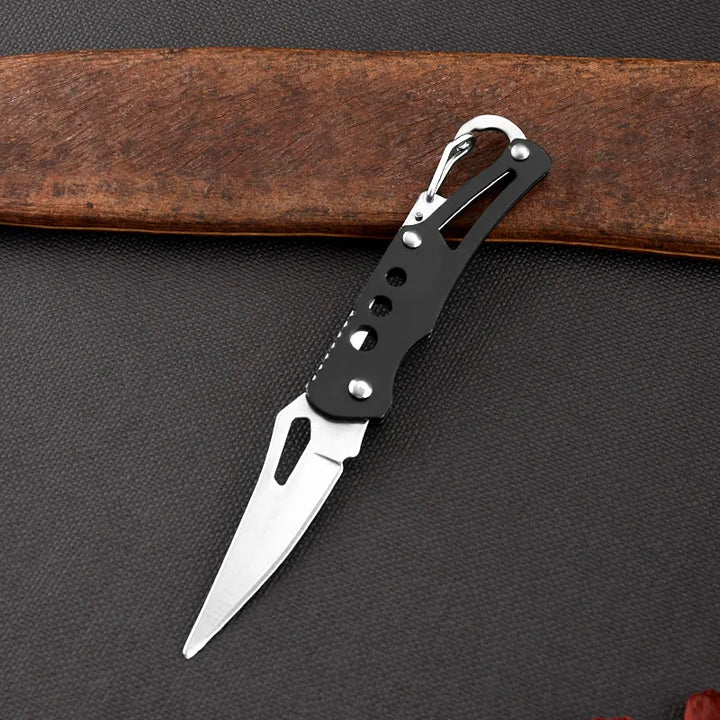 Small pocket knife with a black handle on a dark surface