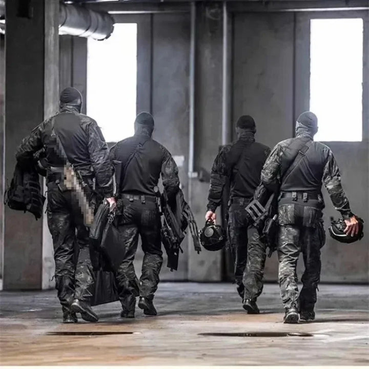 Four individuals in tactical gear walking through an industrial setting.