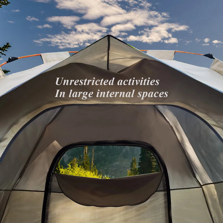 Tent with a view of trees and mountains through the door, against a blue sky.